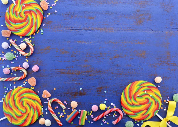 Bright rainbow lollipop candy on dark blue wood table. — Stock Image Bright rainbow lollipop candy on dark blue wood table. Stock Picture