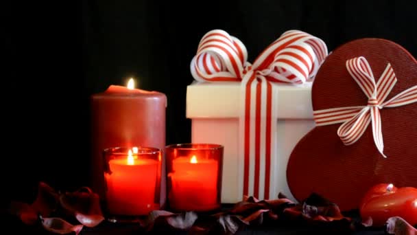 Romántico San Valentín gran pila de regalos rojos a la luz de las velas sobre un fondo negro, acercar . — Vídeos de Stock