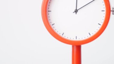 The clock has no numbers to show. It is a clock with symbols for numbers. A white dial watch The edge of the watch is orange. The part of the background is solid white, showing the time 12.00 - 01.00 or 1 hour.