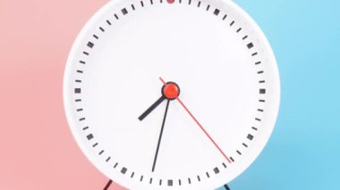 The white clock rotates at a speed for 3 hours. From 7.00 AM - 10.00 AM or 7.00 PM - 10.00 PM, shows the time of day and night. The second hand is red. The minute and hour hands are black. There are two color backgrounds, blue and pink.