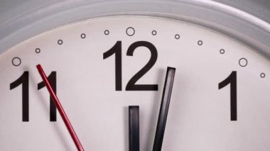 The white clock shows 12.03 p.m.The dial clearly shows the number 12, with a red second hand, slowly walking in time The hour hand. And the minute hand is black It has a white background.