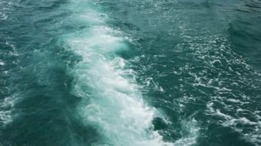 Gemi denizin yüzeyinde yelken açtıktan sonra dalgalar oluştu. Sıcak ve güneşli bir günde deniz sakin ve berrak.