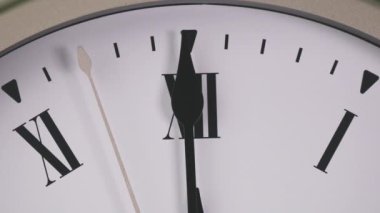 Kısa ve uzun eller Roma rakamlarına göre saat 12 'yi gösteriyor. Öğlen ve gece yarısını gösteriyor. Kadranda beyaz semboller ve siyah eller var..