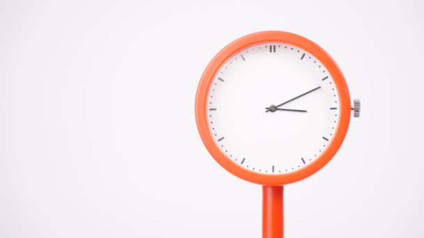 时间流逝 橙色墙上的时钟告诉人们跑步的时间 钟表又短又长的手在转动 白色的背景 — 图库视频影像