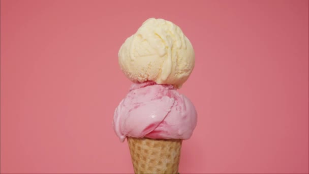 随着时间的流逝 香草和草莓冰淇淋融化在蛋筒上 冰淇淋慢慢地从蛋筒里流出 粉红的背景 — 图库视频影像