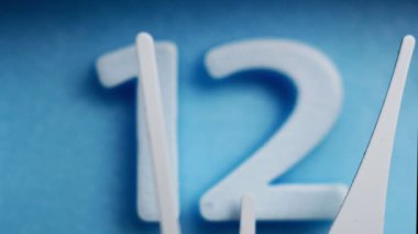 Close up, Operation of the second hand. The short hand points to the number twelve. on a blue background.
