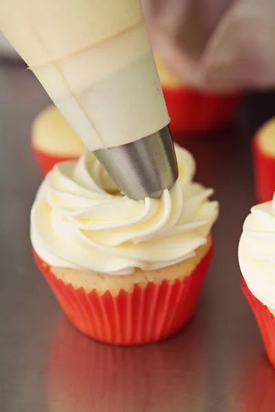 Cobertura sendo aplicada a um cupcake de baunilha — Fotografia de Stock