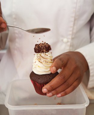 Sprinkles being applied to chocolate cupcake clipart
