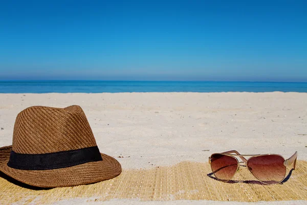 Καπέλο και γυαλιά ηλίου σε μια παραλία το καλοκαίρι — Φωτογραφία Αρχείου