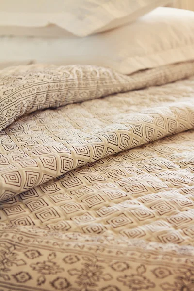 Close up of folds of luxury quilt and pillow in background — Stock Photo, Image