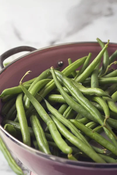 Gros plan d'une passoire rose aux haricots verts lavés — Photo