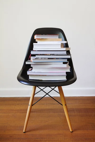 Contemporary black dining chair with stack of books — Stock Photo, Image