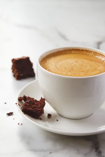 拿铁咖啡杯子和碟子上摇摇欲坠的巧克力布朗尼 — 图库照片