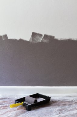 Half painted wall with roller and tray with space for text clipart