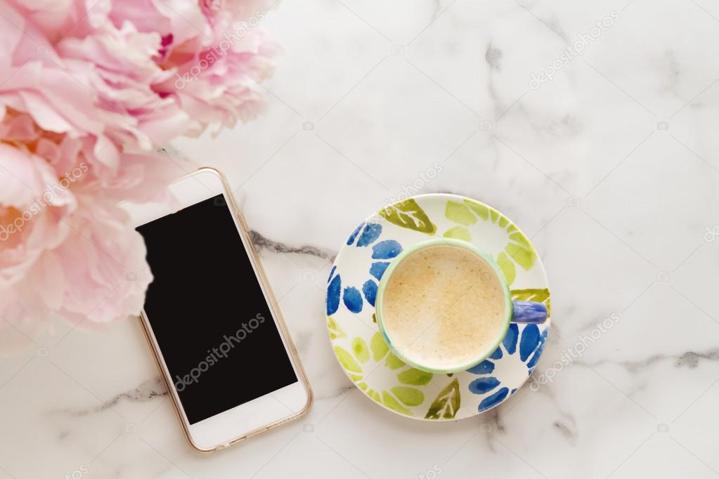 Overhead of coffee, mobile phone and flowers