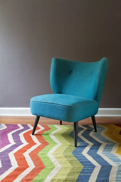 Einzelner teal blauer Sessel und buntes Chevron-Muster Teppich-Interieur — Stockfoto