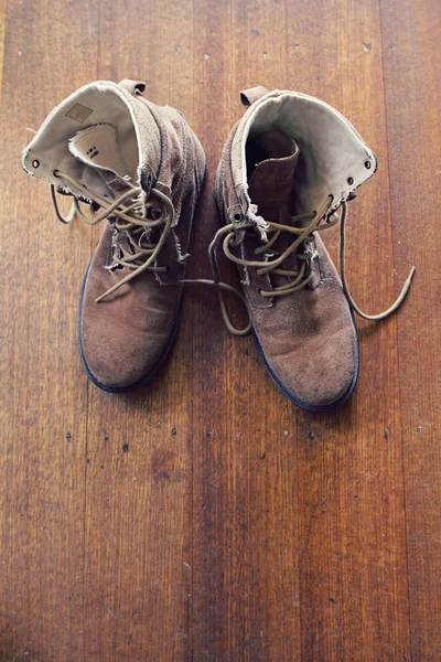 Overhead of worn old work boots on wooden floor — Stock Photo, Image