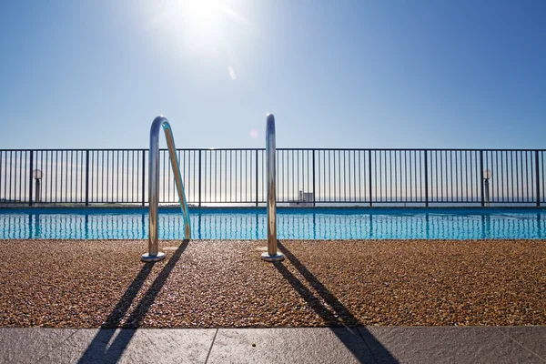 Edge of swimming pool with sun flare in background — Stock Photo, Image