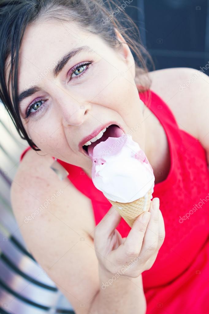 Close up of woman eating an ice cream in a red dress