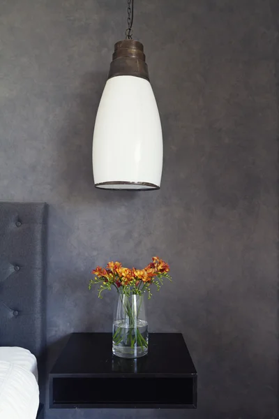 Närbild på hänge ljus och blommor på sängen sidobord — Stockfoto