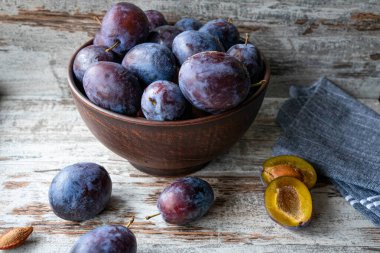 Taze olgun erikler ahşap kasede, köy masasında.