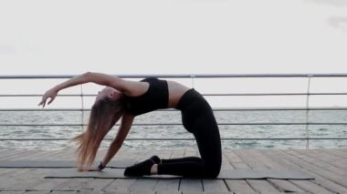 Sahilde okyanusun kıyısında yoga yapan bir kız.