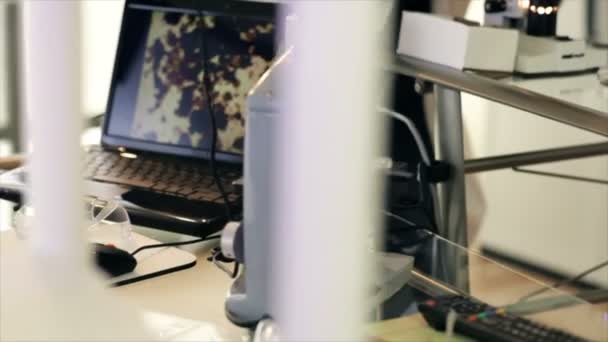 technicien de laboratoire regardant à travers le microscope dolly 