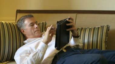 tablet PC'yi kullanma kanepede döşenmesi olgun adam