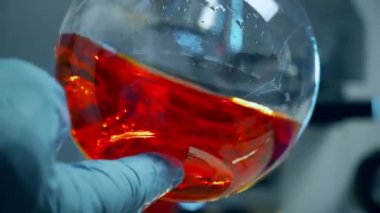 kimyager kırmızı kimyasal içeren şişesi swirls