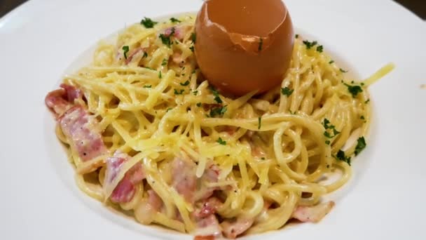 Pâtes carbonara dans une assiette blanche avec oeuf cru — Video