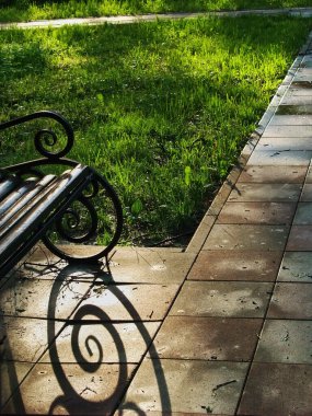Park yolundaki banktan gölgeler, yaz aylarında