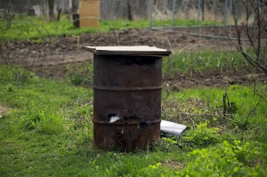 Baharda, bahçede eski demir fıçı.