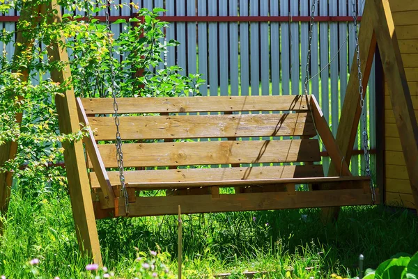 large wooden swing in the garden, in summer