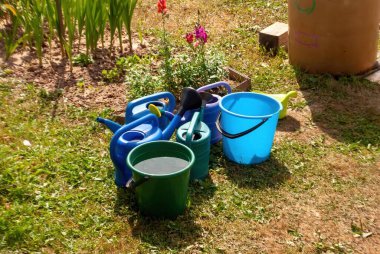 Yazın, bahçede plastik kovalar ve su bidonları.