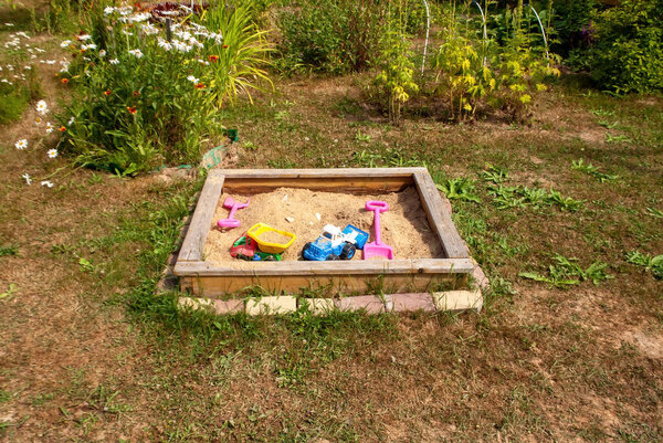 children's toys in a sandbox in the village, in summer