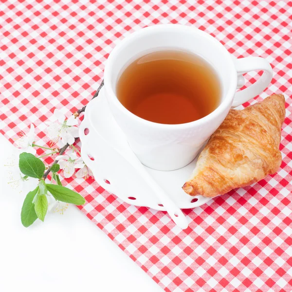 Taza de té con croissant y una ramita de flores de cerezo —  Fotos de Stock
