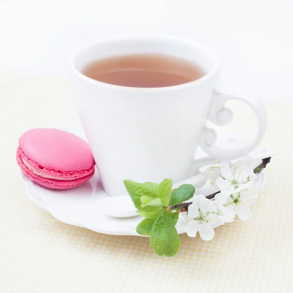 Cup of tea and sweet and colourful strawberry french macaroon an — Stock Photo, Image