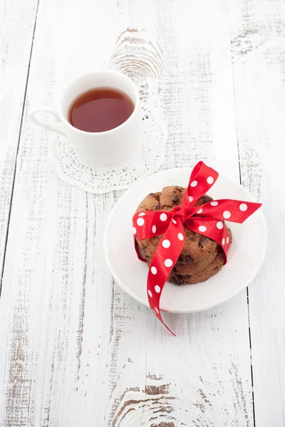 Galletas con chispas de chocolate en un plato blanco con taza de té —  Fotos de Stock