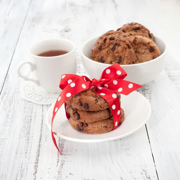 Galletas con chispas de chocolate en un plato blanco con taza de té —  Fotos de Stock