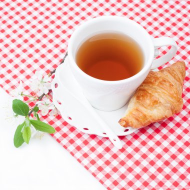 Çay bardağı kruvasan ve kiraz çiçekleri bir delikanlı ile