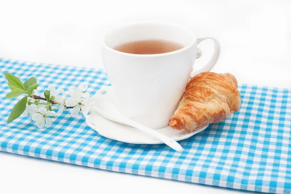 Çay bardağı kruvasan ve kiraz çiçekleri bir delikanlı ile