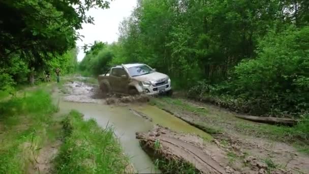 Брудний пікап проїжджає через болотисту калюжу в лісі і людина знімає його. — стокове відео