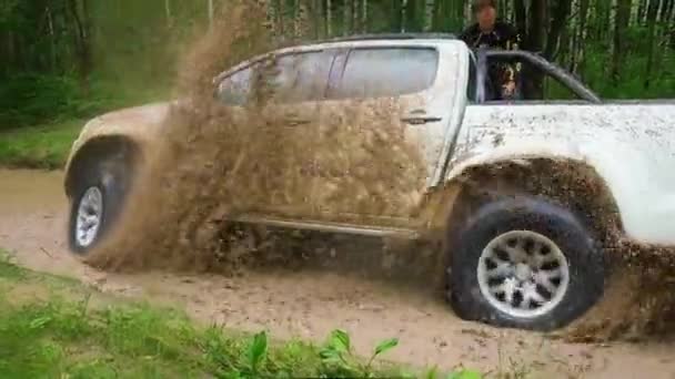 Pickup truck stuck in a puddle. Wheels slipping and pouring car and man with mud — Stock Video