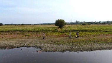 Gençler elektrikli tek tekerlekli bisiklete binerler. Bir köy yolunda.