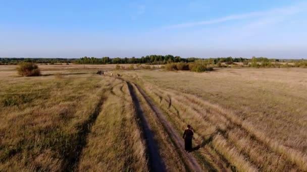 Um homem monge monta um monociclo elétrico através do campo. — Vídeo de Stock