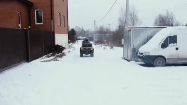 Köyde iki adam ATV 'ye biniyor.