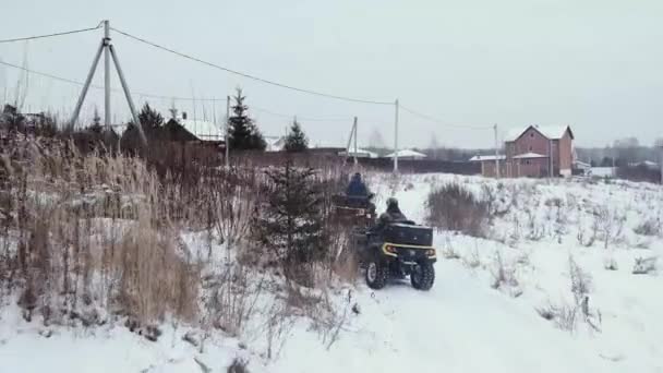 Οι άνδρες οδηγούν ΑΤV σε ένα χιονισμένο δρόμο — Αρχείο Βίντεο