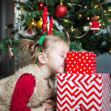 Noel ağacının arka planında yeteneği olan bir çocuk. Mutlu kız sarılır ve sarılır..