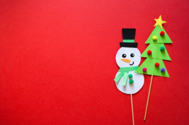 Çocuklar için kağıt işi. Kırmızı arka planda yeşil Noel ağacı. Çocuklar için sanat yaratmak. Kopyalama alanı olan en küçük yeni yıl kavramı.