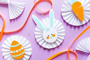 Çocuklar için paskalya kâğıdı. Kağıt boyanmış yumurta, tavşancık ve mor arka planda havuç. çocuklar için sanat oluştur
